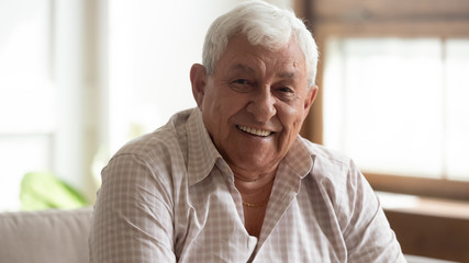 Fototapeta na wymiar Headshot portrait of happy elderly man feel optimistic at home