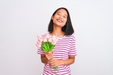 Young chinese woman holding bouquet of roses standing over isolated white background with a happy face standing and smiling with a confident smile showing teeth