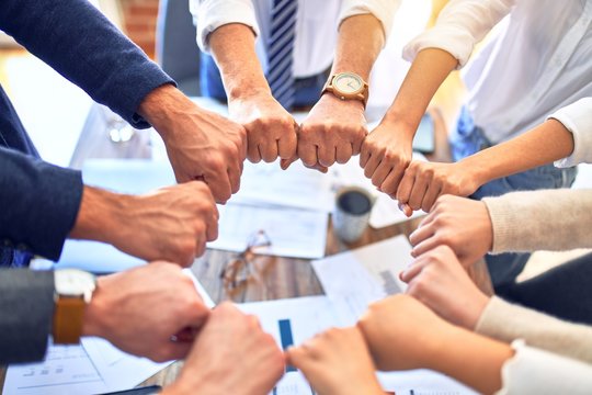 Group of business workers standing bumping fists at the office