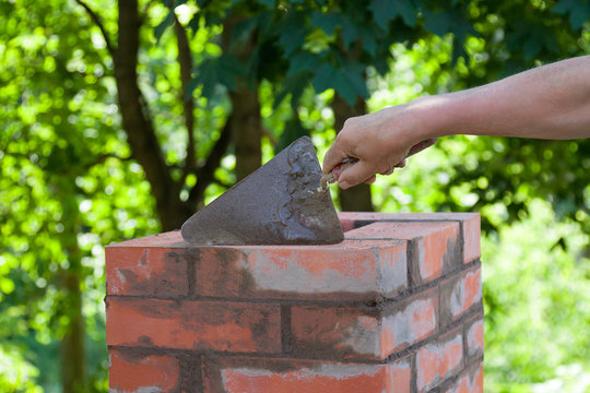 Masonry Works,  Male Hand Working With A Trowel, Repairing A Chimney From Red Bricks On A Roof