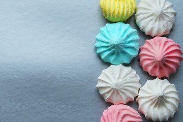 Bright colored meringues in blue, pink and white on a gray background on the right. Homemade cake. Selective focus. The view from the top