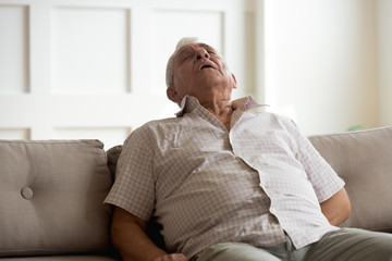 Exhausted elderly man fall asleep on couch at home