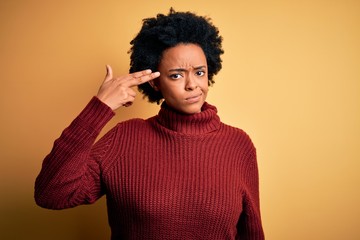 Fototapeta na wymiar Young beautiful African American afro woman with curly hair wearing casual turtleneck sweater Shooting and killing oneself pointing hand and fingers to head like gun, suicide gesture.