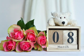 March 8 text on wooden block calendar and pink roses and bear.Greeting card with pink roses .Spring card template. Women's Day. Greeting card for mother's day. Flower card. Copy space.