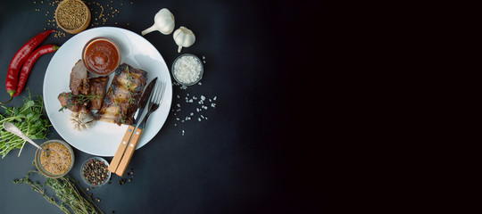 Baked ribs in a white dish. . Grilled pork ribs with spices and fresh herbs. Meat dishes. Dark...