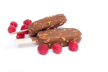 Chocolate ice cream with nuts, on a stick and a raspberry lying nearby. Concepts of healthy, tasty, nutrition.