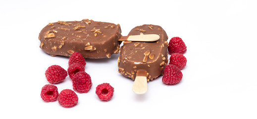 Chocolate ice cream with nuts, on a stick and a raspberry lying nearby. Concepts of healthy, tasty, nutrition.