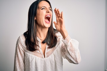 Young brunette woman with blue eyes wearing casual t-shirt over isolated white background shouting and screaming loud to side with hand on mouth. Communication concept.