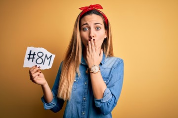 Beautiful woman with blue eyes celebrating 8th march womens day over yellow background cover mouth...