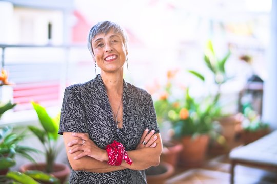 Middle age beautiful grey-haired woman wearing dress and bandana on wrist smiling happy and confident standing with a smile on face at terrace