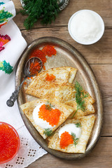 Homemade pancakes with red caviar, sour cream and dill served with vodka. Rustic style.