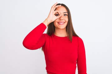 Young beautiful girl wearing red casual t-shirt standing over isolated white background doing ok gesture with hand smiling, eye looking through fingers with happy face.