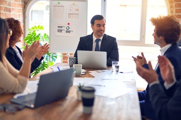 Group of business workers smiling happy and confident in a meeting. Working together looking at presentation using board and laptop applauding at the office.