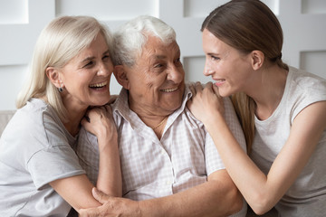 Portrait of happy elderly parents and adult daughter hugging