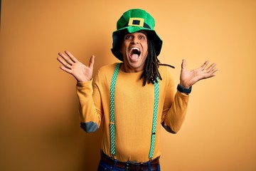 Young african american man wearing green hat celebrating saint patricks day celebrating crazy and amazed for success with arms raised and open eyes screaming excited. Winner concept