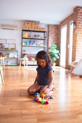Fototapeta premium Beautiful toddler girl sitting on the floor playing with train at kindergarten
