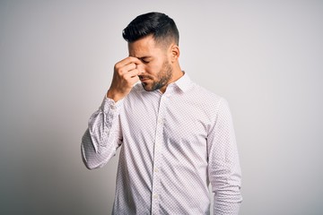 Young handsome man wearing elegant shirt standing over isolated white background tired rubbing nose and eyes feeling fatigue and headache. Stress and frustration concept.