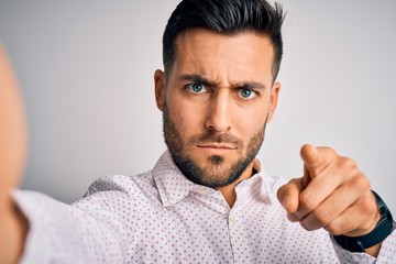 Young handsome man wearing shirt making selfie by the camera over white background pointing with...