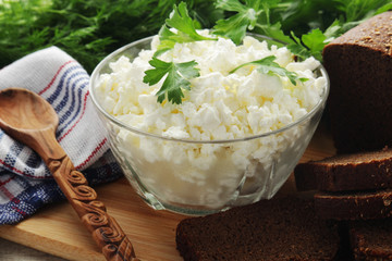 A bowl with cottage cheese, a bunch of green and rye bread