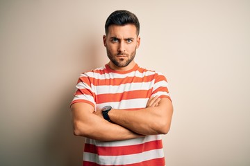 Young handsome man wearing casual striped t-shirt standing over isolated white background skeptic...