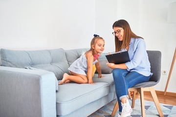 Young therapist woman speaking and treating child, counselor and behaviour correction at pedagogue payroom taking notes on clipboard