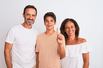 Obraz premium Family of three, mother, father and son standing over white isolated background showing and pointing up with finger number one while smiling confident and happy.