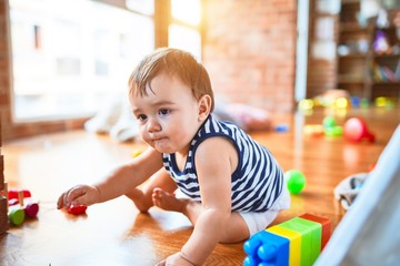 Adorable toddler playing around lots of toys at kindergarten