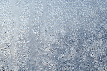 Frozen drops of condensed steam water drops on the transparent window glass. Clean background. Condensation of moisture at extreme temperatures. Water vapor condenses on cold window glass and freezes