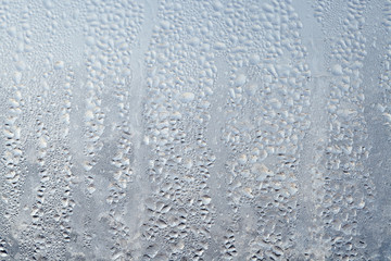 Texture of Frozen drops of condensed steam water drops on the transparent window glass. Clean background. Water vapor condenses on cold window glass and freezes into ice