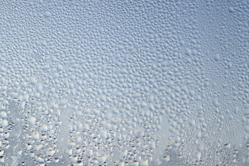 Texture of Frozen drops of condensed steam water drops on the transparent window glass. Clean background. Water vapor condenses on cold window glass and freezes into ice