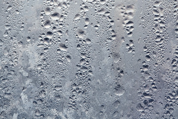 Texture of Frozen drops of condensed steam water drops on the transparent window glass. Clean background. Water vapor condenses on cold window glass and freezes into ice