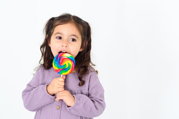 Happy smiling child eating colorful sweet lollipop and having fun over white background.