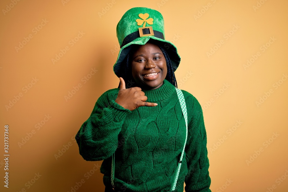 Wall mural plus size african american woman with braids wearing green hat with clover on st patricks day smilin