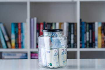 20 euro € bills banknotes in glass jar on the white table at home money saving or investment business retirement concept