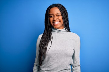 Young african american woman standing wearing casual turtleneck over blue isolated background...