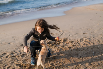 Long-haired girl in warm clothes by the North sea with puppy