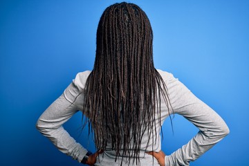 Young african american woman standing wearing casual turtleneck over blue isolated background standing backwards looking away with arms on body