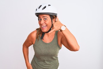 Middle age mature cyclist woman wearing safety helmet over isolated background smiling doing phone gesture with hand and fingers like talking on the telephone. Communicating concepts.