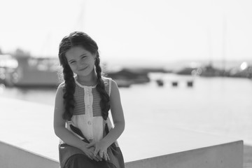 Portrait of a beautiful little girl with long hair near the lake on a sunny day. Black and white.