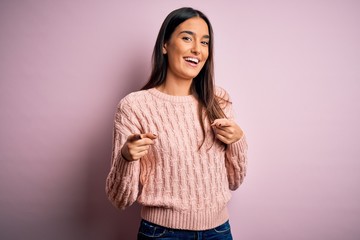 Young beautiful brunette woman wearing casual sweater over isolated pink background pointing fingers to camera with happy and funny face. Good energy and vibes.