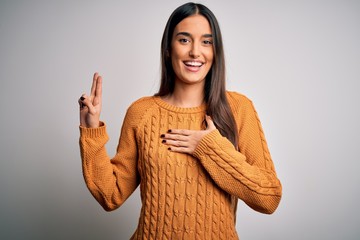 Young beautiful brunette woman wearing casual sweater over isolated white background smiling...