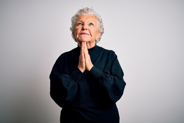 Senior beautiful woman wearing casual black sweater standing over isolated white background begging and praying with hands together with hope expression on face very emotional and worried. Begging.