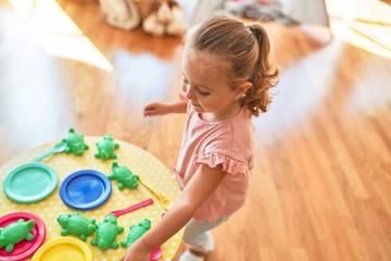 Beautiful blond toddler girl playing  meals using plastic food at kindergarten
