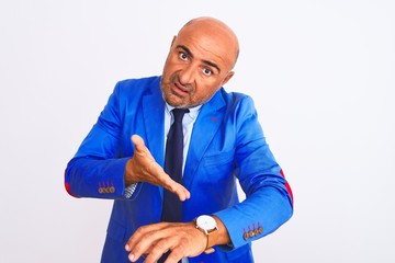 Middle age businessman wearing suit standing over isolated white background In hurry pointing to...