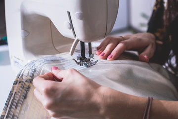 Process of sewing the curtains at home, close up of curtain tape on the sewing machine, hemming,...