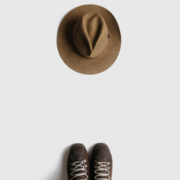 Vintage hiking boots and hat on white background isolated. Minimalist backpacking travel concept flat lay.