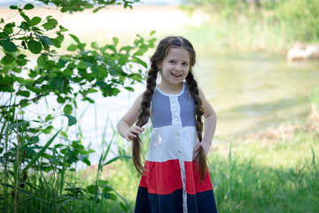 Portrait of a beautiful little girl with long hair on a background of nature on a sunny day.