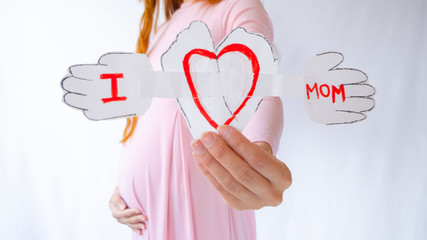 A pregnant woman is holding a heart in her hands