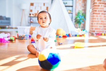 Fototapeta premium Beautiful infant happy at kindergarten around colorful toys