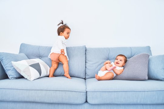 Beautiful infant happy girls playing together at home kindergarten sitting on the sofa